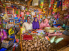A man and two women smile as they stand inside the store they manage filled with various goods and produce.