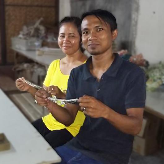 A woman and a man artisan show bracelets they worked on.