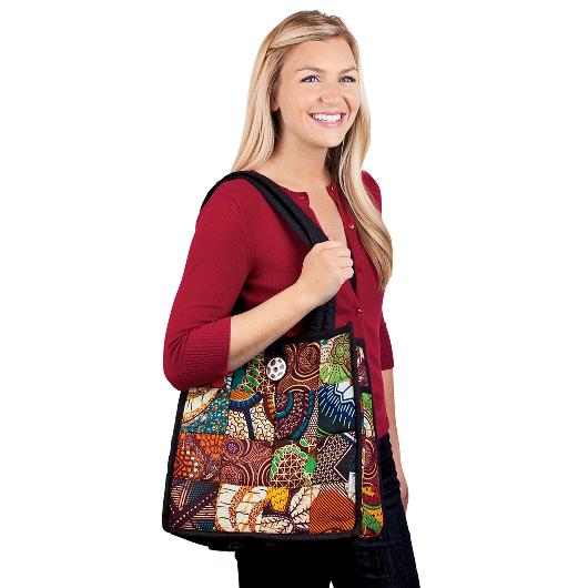 A woman wearing a red top carries a patchwork tote bag on her right shoulder.