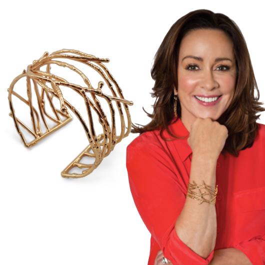 Patricia Heaton displaying a brass bracelet that she is wearing on her right arm.