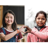 Two young girls join hands to form a heart.